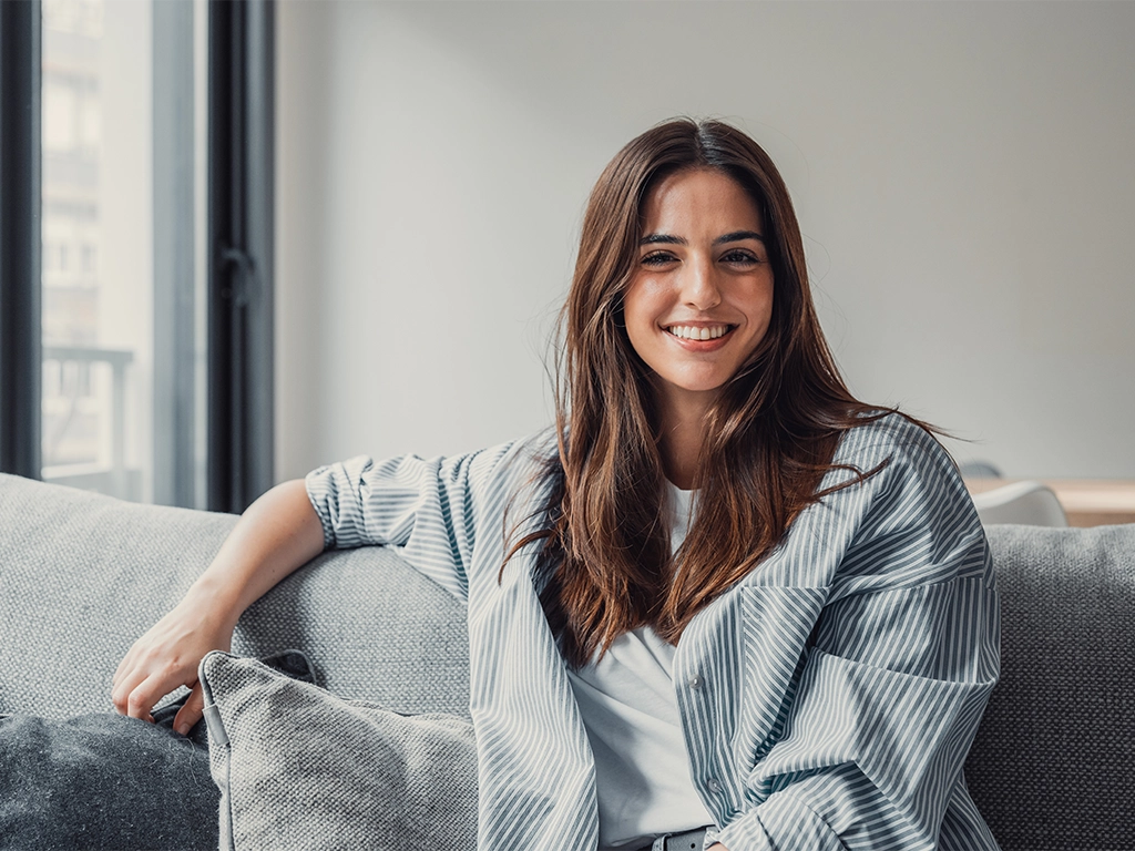 Woman relaxing at home with confident smile from SureSmile Clear Aligners