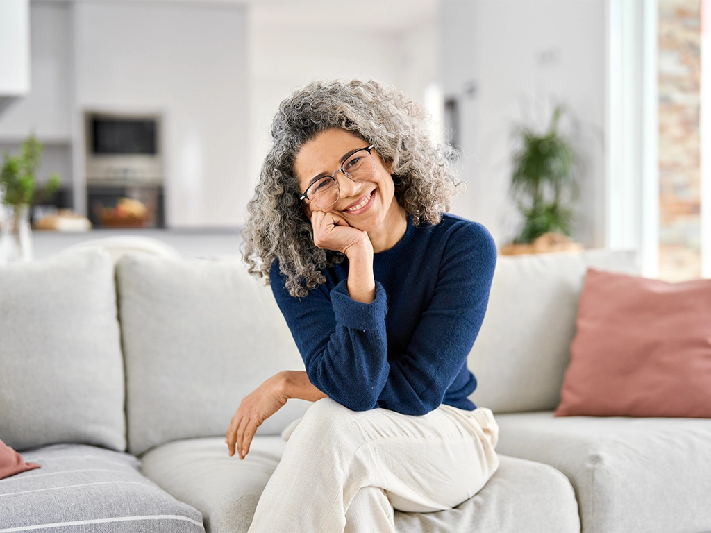 Smiling older woman at home showing confident smile with dentures